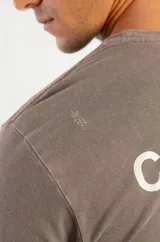 Remera de algodón color marrón con efecto lavado, cuello redondo y estampa pequeña en el pecho con la frase Coffee & Vodka.