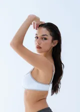 Microtop deportivo de color blanco con ribetes en color gris claro, de corte bajo y tirantes finos.