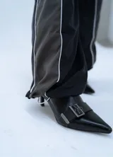 Pantalon deportivo de estilo urbano, confeccionado en tela técnica, con cintura elástica ajustable mediante cordón. Presenta un diseño bicolor en negro y gris oscuro con líneas laterales en contraste.