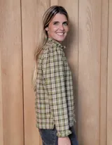 Camisa de manga larga con estampado de rayas verticales en tonos blanco y lila. Presenta cuello alto con volados, cierre frontal con doble botonadura y puños con volados.