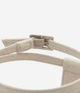 Sandalia tipo flatform color beige, con diseño de tiras finas, dedal metálico en la parte frontal y cierre con hebilla en el talón. Suela plana de altura media.