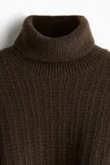 Polera de punto texturizado en color marrón oscuro, con cuello alto acanalado y puños y bajo con terminación acanalada. Presenta un corte estándar.