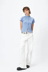 Top blanco de tejido de punto acanalado, con cuello alto, mangas cortas y abertura central en el ruedo.