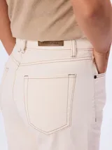 Bermuda de jean color beige, de tiro medio y corte recto, con bolsillos laterales y traseros, y presillas para cinto.