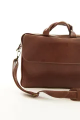 Portafolio de cuero color marrón, con asas superiores reforzadas, correa ajustable desmontable para el hombro y bolsillo exterior con solapa. Diseñado para oficina y uso profesional.
