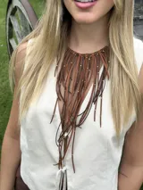 Collar con cuello rígido y flecos de gamuza y tiento sintético con detalles de mostacillas metálicas.