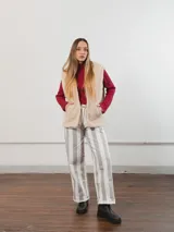 Chaleco color crema con textura de piel sintética, sin mangas y con forro interno.