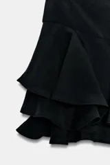 Shorts de tiro medio confeccionado en mezcla de viscosa, con diseño de volantes en el bajo y cierre lateral con cremallera oculta.