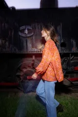Camisa de seda con estampado floral en tonos naranjas y rosados, de corte amplio y estilo boho. Presenta mangas largas abullonadas, frunces en hombros y espalda, y cierre frontal con botones.