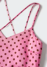 Vestido midi de tejido satinado en color rosado con estampado de lunares marrones. Presenta un diseño recto, cuello escotado y tirantes finos dobles que se cruzan en la espalda abierta.
