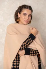 Ruana abierta de color beige, confeccionada en tejido de punto con terminación de flecos en el ruedo.