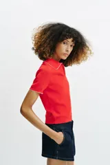 Top de punto color crudo, con cuello polo y escote en V. Cuenta con mangas cortas y detalle de puntilla con forma de onda en el cuello y los puños.