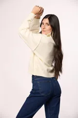 Buzo tejido de punto con cuello alto y cierre frontal parcial. Presenta mangas largas con puños acanalados y un diseño de corte holgado.
