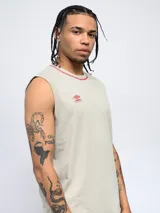 Musculosa deportiva Umbro de color beige con cuello redondo en contraste de color rojo. Presenta el logo de la marca bordado en el pecho.