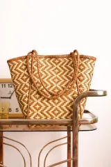 Bolso tipo tote de cuero trenzado color tostado con diseño geométrico.