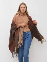 Ruana tejida con diseño colorblock en tonos de gris y beige, con flecos en el borde inferior.