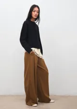 Pantalón de vestir color marrón, de corte amplio y fluido, con tiro alto y diseño recto de perneras anchas.