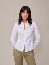 Camisa blanca de algodón con cuello clásico, corte entallado y mangas largas.