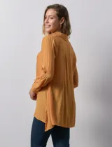 Camisa larga de rayón, con cuello clásico, cierre frontal con botones y mangas regulables con presilla. Presenta un diseño holgado con tajos laterales en el ruedo.