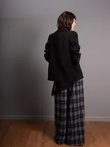 Blazer de corte clásico en color negro, con solapas, hombreras y cierre frontal con un botón. Presenta una textura acanalada similar al terciopelo y bolsillos decorativos en el frente.