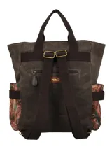 Mochila de diseño patchwork en tonos marrones, confeccionada en una combinación de pana, tela encerada y tejido estampado. Cuenta con un bolsillo frontal con cierre, manijas superiores fijas, correas ajustables y un llavero decorativo con borlas y cuentas colgando de un lateral.