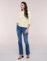 Cardigan de punto fino color amarillo con escote a la base, mangas tres cuartos y abotonadura frontal con botones metálicos decorativos.