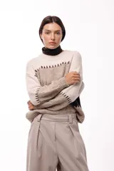 Sweater de tejido de punto grueso con diseño de bloques de color en tonos beige, marrón y bordó. Presenta un corte relajado, mangas amplias y detalles de costuras visibles en contraste que separan las franjas de color.