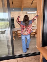Camisa oversize combinada de denim azul y tela vintage con estampado geométrico multicolor en tonos rojos, naranjas y celestes. Cuenta con cierre frontal de botones, cuello camisero y mangas largas.