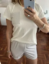 Pijama de dos piezas compuesto por remera blanca de manga corta con bolsillo estampado y short gris con estampado de lunares blancos. El short tiene cintura elastizada.