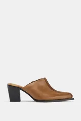 Zueco de piel color camel, con puntera cuadrada y pespunte decorativo en el empeine. Posee un taco alto y grueso de color negro.