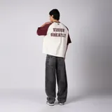 Remera estilo raglán color crudo con mangas y cuello en bordó, de manga corta, corte relajado y detalles estampados en el pecho.