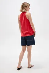 Musculosa de viscosa color rojo, con cuello halter, corte ajustado al cuerpo y detalle de cordones con cuentas en el escote.