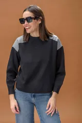 Sweater de punto color negro con cuello redondo y mangas largas, destacando por sus paneles de cuero sintético gris en los hombros.
