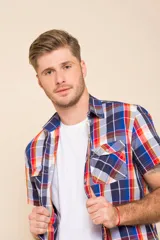 Camisa de manga corta con estampado de cuadros en tonos verdes, azules y blancos. Presenta cuello clásico, cierre frontal con botones y dos bolsillos delanteros con solapa.