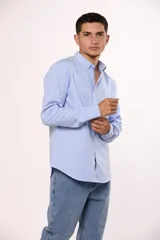 Camisa de manga larga en color gris, confeccionada en algodón, con cuello abotonado y cierre frontal de botones.