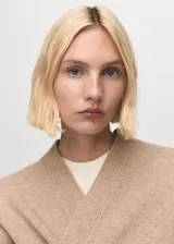 Abrigo largo de tejido de punto en color beige, con diseño recto, cuello solapa y manga larga. Presenta un corte abierto sin cierre frontal.