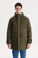 Campera parka larga color verde militar con capucha forrada en piel sintética. Tiene cierre frontal con cremallera y botones a presión, cuatro bolsillos delanteros con solapa y puños ajustables con botones.