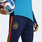Pantalón de entrenamiento Adidas Tiro España 26, color azul marino con detalles en celeste y franjas laterales en amarillo y rojo. Incluye logo de Adidas en amarillo y tecnología Formotion.