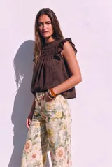 Blusa sin mangas de color crudo, con diseño oversize, cuello redondo y detalles de nido de abeja bordado en el pecho, acompañado de volados en los hombros.