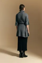 Poncho de tejido de punto color gris, con cuello alto y mangas amplias de diseño holgado.