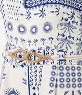 Enterito corto sin mangas de viscolino, con escote en V y estampado tipo patchwork en tonos blanco y azul marino, con motivos tropicales como palmeras y patrones geométricos. Incluye trabillas en la cintura y cinturón de cuerda trenzada.