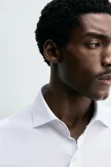 Camisa de corte regular fit confeccionada en tejido de algodón con textura. Presenta cuello italiano, manga larga con puños abotonados y cierre frontal de botones.