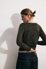 Chaqueta de punto de manga larga y cuello redondo, con cierre frontal de botones y estampado animal print en tonos marrones y negros.