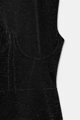 Vestido corto negro con brillo, cuello redondo y manga sisa. Presenta un detalle de aplicación de hilo metalizado y bajo recto.