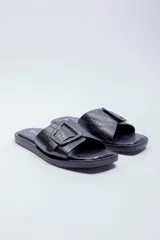 Sandalias planas Paddock modelo Amelias, de color negro con textura efecto cocodrilo. Presentan una tira ancha en el empeine decorada con una hebilla grande cuadrada del mismo material y tono.