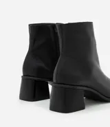 Bota de cuero de caña media para mujer, con punta cuadrada y tacón bloque de 6 cm. Presenta un cierre de cremallera en el lateral interno y una costura central decorativa en la parte frontal.