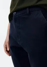 Pantalón de vestir color verde oscuro, de corte slim, con bolsillos laterales y traseros. Se ajusta a la cintura con botón y cierre.