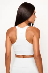 Top deportivo de alto rendimiento con diseño de espalda nadador, confeccionado en tejido técnico con protección UV50+. Presenta un bolsillo interno en el forro frontal y detalles reflectivos.