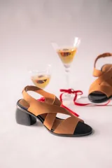 Sandalias de neopreno color marrón con tiras cruzadas en el empeine y puntera abierta. Cuentan con un taco irregular de 6 cm de altura y plantilla de cuero.