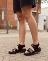Sandalias Zenda de cuero negro con tiras delanteras de charol, ajuste con velcro y suela chunky de goma con plataforma.